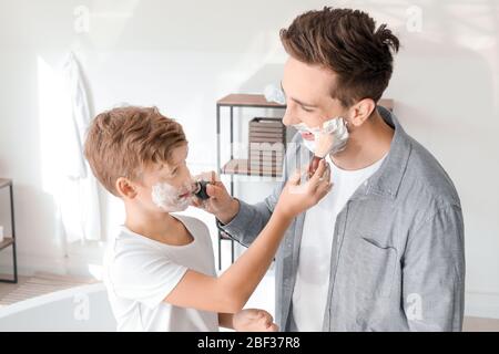 Padre con hijo aplicando espuma de afeitar en sus caras en el baño Foto de stock