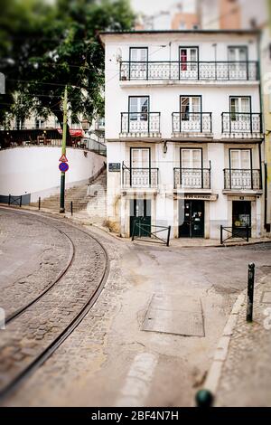 Edificio blanco con balcones en el barrio Alfama de Lisboa, junto a las vías del tranvía eléctrico Foto de stock