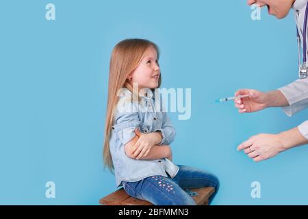 Una joven pediatra realiza una vacunación de una niña pequeña. Foto de stock