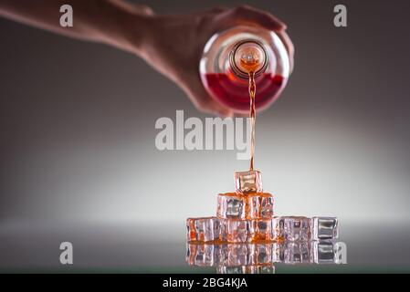 Verter la bebida roja sobre cubitos de hielo; mezclar bebidas- imagen conceptual