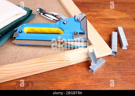 Grapadora de construcción con telas y grapas en caja de madera
