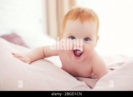 feliz bebé emocionada niña arrastrándose en la cama Foto de stock