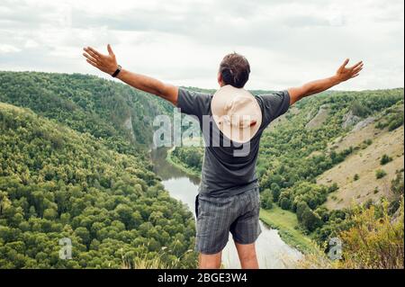 Excursionista con mochila en la cima de una montaña con las manos levantadas