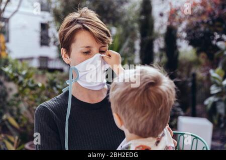 Littley niño ayudando a su madre a ponerse una máscara facial