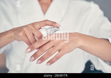 Mujer sosteniendo una botella de producto para el cuidado de la piel Foto de stock