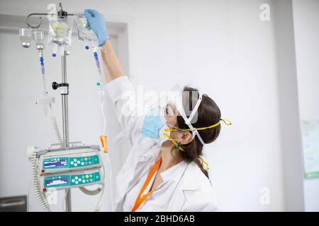 Una enfermera profesional de ICO una bolsa para el tratamiento de quimioterapia un paciente mientras usa una máscara facial como precaución contra la crisis del COVID El Institut