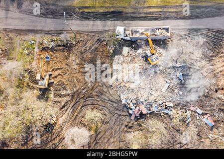 excavadora amarilla cargando camión volquete en sitio de demolición. vista superior aérea Foto de stock