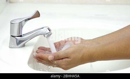 Lavarse las manos con agua antes de aplicar jabón, protección contra la infección por coronavirus COVID-19 Foto de stock