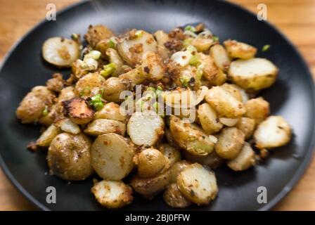 Plato de patatas fritas, salteado con anchoas, cebolletas y pan rallado. -