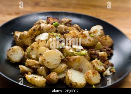 Plato de patatas fritas, salteado con anchoas, cebolletas y pan rallado. -