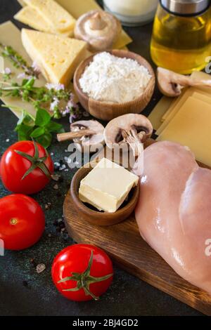 Comida fondo italiano. Ingredientes para cocinar lasaña con pollo y champiñones sobre un fondo de piedra oscura.