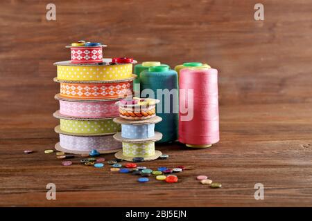 Bobinas de cinta de color y botones sobre fondo de madera