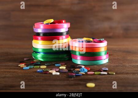 Bobinas de cinta de color y botones sobre fondo de madera