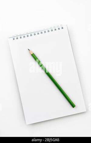 Abra el cuaderno con un lápiz Graphite verde sobre una mesa de oficina blanca Foto de stock