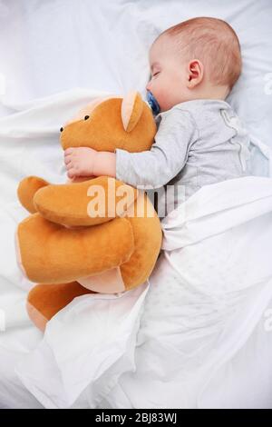 Bebé durmiendo sobre el regazo de un oso de peluche Stock Photo