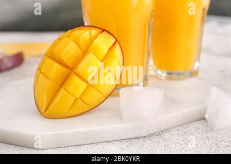 Sabroso mango maduro y vasos de zumo en la mesa Foto de stock