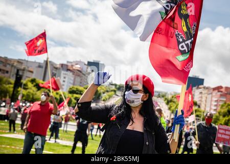 Una mujer con máscara sostiene una bandera de Portugal durante el rally del día Internacional del Trabajo.centenas se reunieron en Lisboa para celebrar el día del Trabajo (Alameda Dom Afonso Henriques) Organizado por el sindicato CGTP, mientras observa estrictas reglas de distanciamiento social en un evento más pequeño de lo habitual para mostrar solidaridad con los desempleados que han quedado a causa del brote de coronavirus. Foto de stock