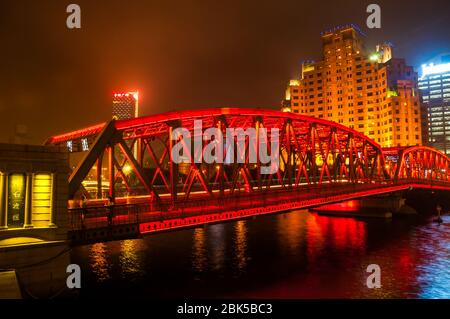 Una fotografía nocturna de un puente iluminado por luces rojas