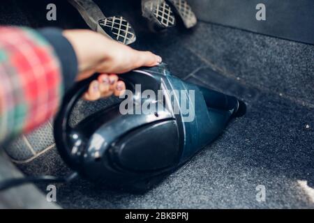 El conductor limpia el coche con una aspiradora pequeña. Mujer se encarga  de la auto usando hoover para deshacerse del polvo en el suelo Fotografía  de stock - Alamy