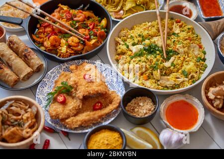 Se sirve comida asiática. Platos, sartenes y cuencos llenos de muelas de pollo salteado y verduras