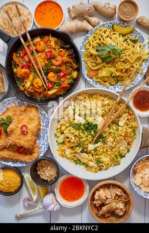 Se sirve comida asiática. Platos, sartenes y cuencos llenos de muelas de pollo salteado y verduras