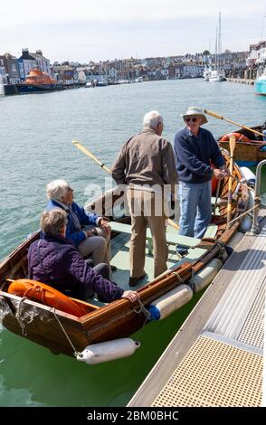 Weymouth, Dorset, Inglaterra, Reino Unido alrededor de 2014. Las personas mayores disfrutan de un viaje por el puerto de Weymouth en un ferry de remo. Foto de stock
