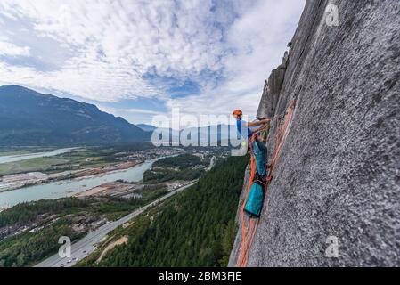 Hombre cargando bolso de transporte mientras escalada en roca en granito con Ver Squamish Foto de stock