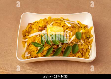 Poha popular plato de desayuno indio saludable hecho con arroz aplanado servido en plato. Foto de stock
