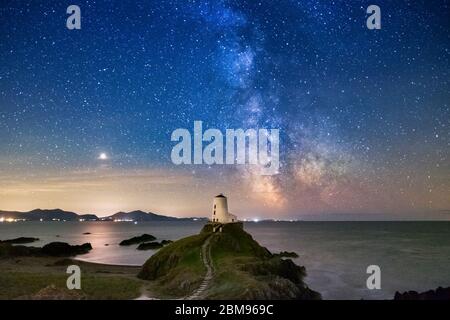 La vía Láctea y el cielo nocturno sobre el faro de Twr Mawr, la isla de Llanddwyn, Anglesey, Gales del Norte, Reino Unido