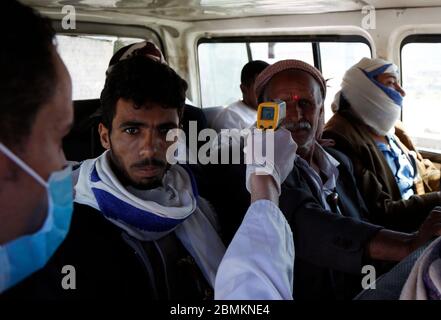 Sanaa, Yemen. 9 de mayo de 2020. Un trabajador de salud controla la temperatura corporal de un viajero en un autobús como medida cautelar contra la propagación de COVID-19 en la entrada sur de Sanaa, Yemen, 9 de mayo de 2020. Crédito: Mohammed Mohammed/Xinhua/Alamy Live News Foto de stock