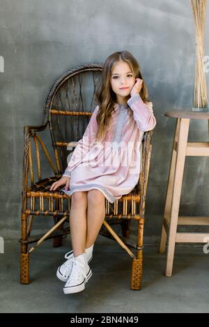 Linda niña de 5-6 años con elegante vestido rosa sobre fondo gris. mirando  a la cámara fiesta de cumpleaños. celebracion.