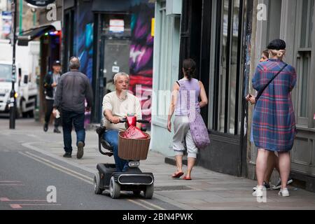 LONDRES, Reino Unido - 17 de septiembre de 2019: Un hombre viaja en una scooter para los ancianos en las tiendas de Bricklane Foto de stock