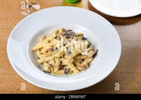 Tradicional pasta auténtica italiana penne al pollo e funghi con setas, pollo y queso parmesano. Foto de stock
