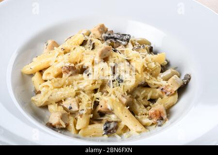 Tradicional pasta auténtica italiana penne al pollo e funghi con setas, pollo y queso parmesano. Foto de stock