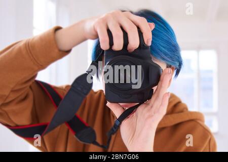 hipster chica sosteniendo cámara y tomando fotos. primer plano de la mano de la joven con cámara profesional en el estudio. concepto del día de la fotografía mundial