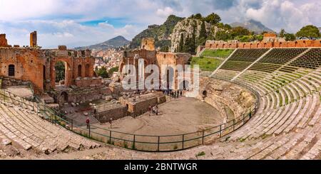 Vista panorámica de las ruinas del antiguo teatro griego, el casco antiguo de Taormina y Castelmola pueblo de montaña en el día soleado, Sicilia, Italia Foto de stock
