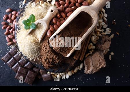Cacao en polvo, chocolate, nueces y especias, sobre una mesa de madera. Fotografía de alimentos Foto de stock