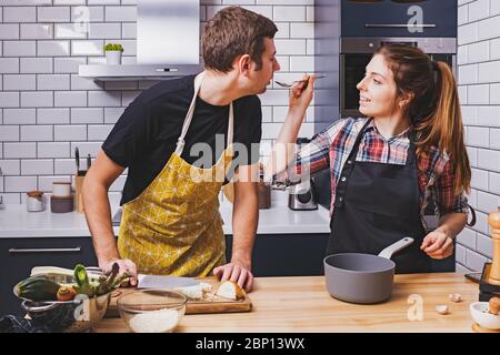 Jóvenes parejas alegres cocinando juntos en casa. Foto de stock