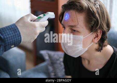 El padre está revisando la temperatura de su hijo con un termómetro infrarrojo en la casa Foto de stock
