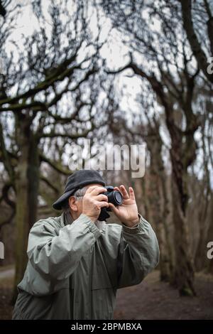 Hombre Senior dedicar tiempo a su pasatiempo favorito - Fotografía - tomando fotos con su cámara digital exterior/DSLR Foto de stock