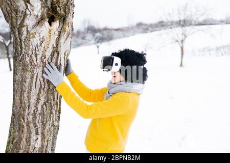 Una niña en un suéter y gafas en invierno se sienta sobre un fondo cubierto  de nieve en el bosque Fotografía de stock - Alamy