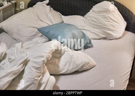 Cama con mantas, sábanas y almohadas desordenados Foto de stock