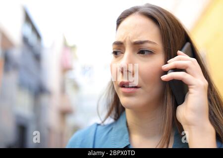 Preocupado mujer hablando sobre smart phone caminando afuera en la calle Foto de stock