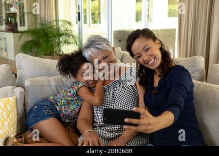 Mujer mixta de raza con su madre mayor y su hija joven tomando un selfie