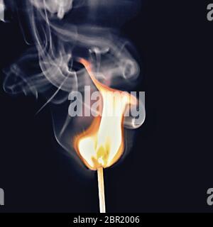 Expresionistas y desarrollo de humo visible la llama de una cerilla ardiendo, aislado sobre fondo negro. El humo forma remolinos de sombras transparentes Foto de stock