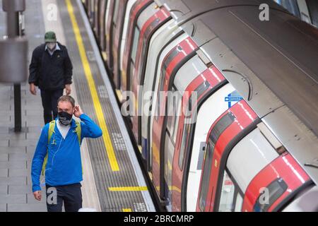 Los viajeros que usan máscaras protectoras en la estación de metro Clapham Common, Londres, como los servicios de tren aumentan esta semana como parte de la relajación de las restricciones de bloqueo coronavirus. Foto de stock