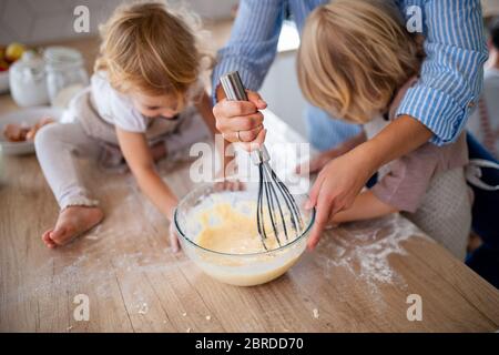 Sección central de la madre con dos niños pequeños en el interior de la cocina, cocina. Foto de stock