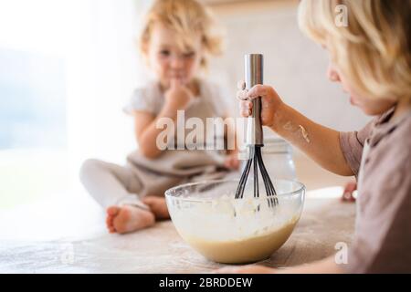 Dos niños pequeños ayudando en el interior en la cocina con cocinar. Foto de stock