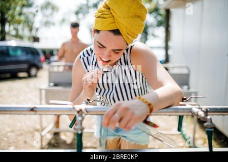 Mujer joven en el festival de verano, cepillando los dientes por los lavabos. Foto de stock