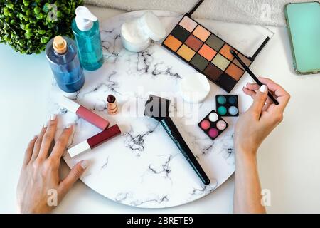 Arriba ver mujer joven haciendo maquillaje en casa - Closeup manos femeninas aplicando maquillaje - Cosméticos y skincare concepto de publicidad Foto de stock